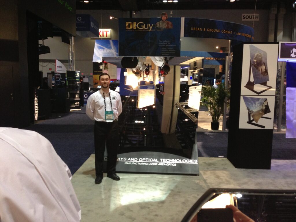 man standing next to a large mirror display at a trade show