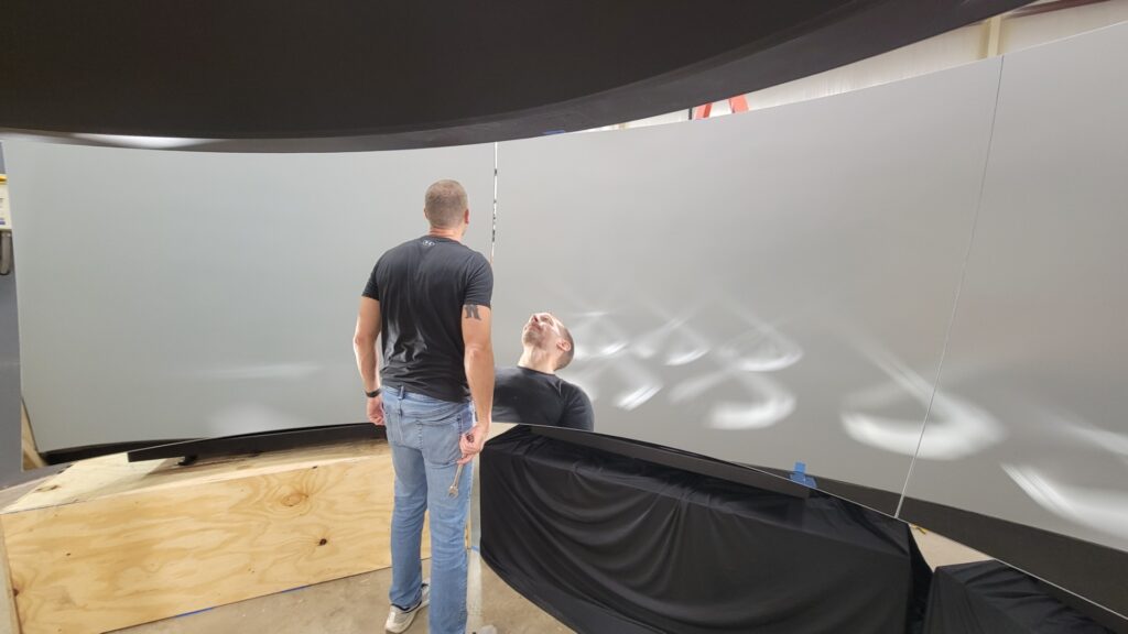 man standing in front of an array of curved mirrors set up into a big curve